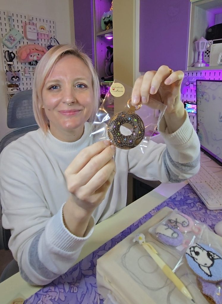 Stefni holding a handmade punch needle donut accessory by LotsaLoops