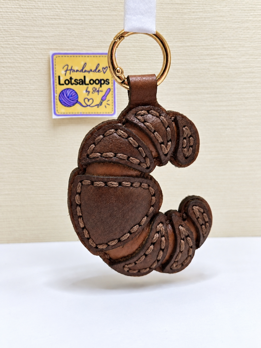 Handmade leather croissant keyring and bag charm with layered hand-stitched detailing