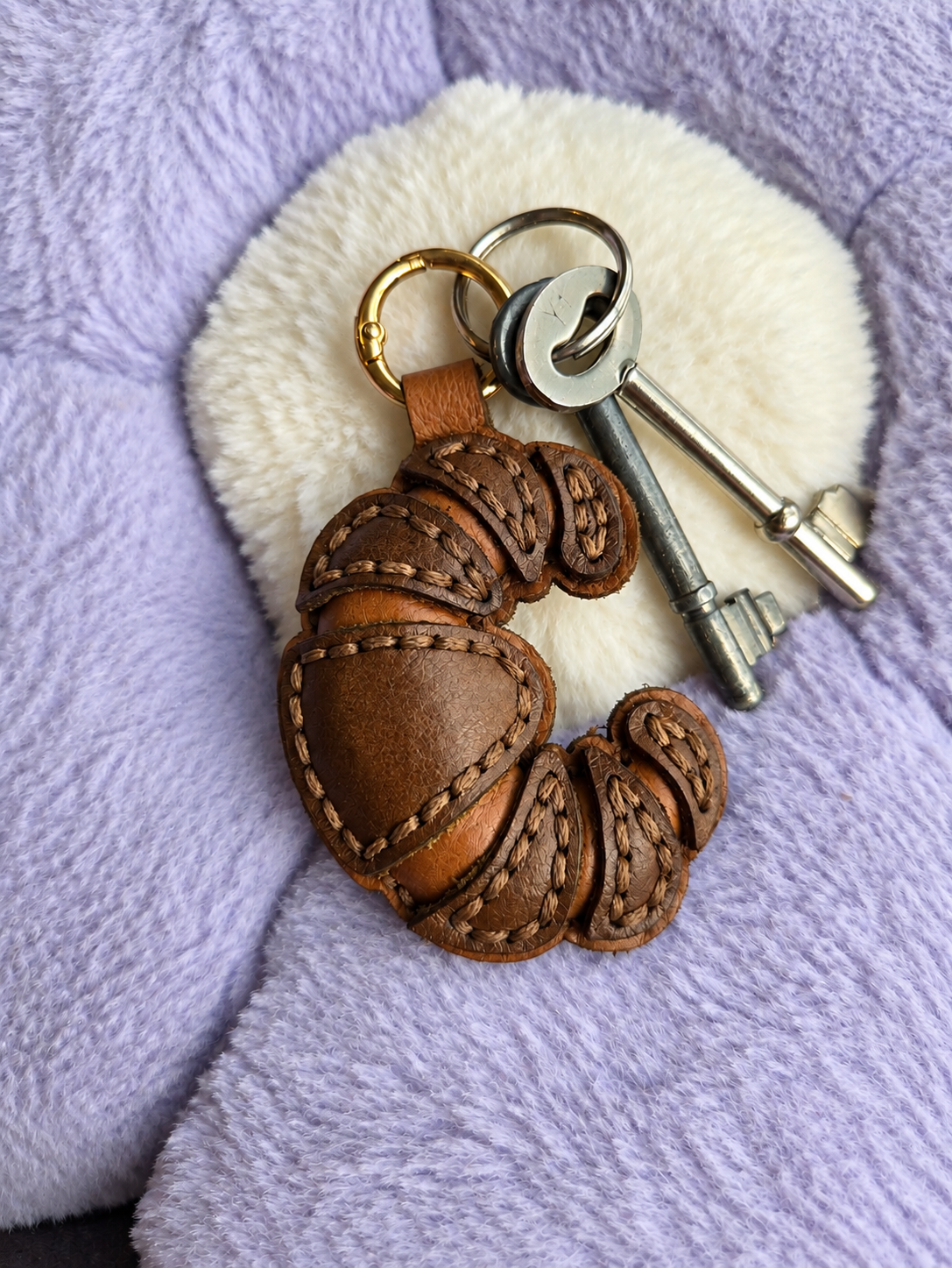 Handmade leather croissant keyring with gold clasp attached to keys