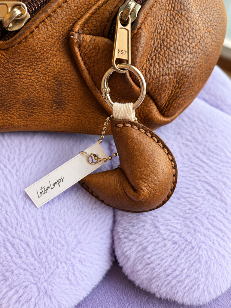 light brown leather fortune cookie keyring and bag charm attached to handbag
