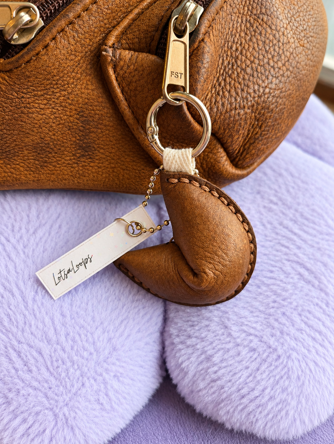 light brown leather fortune cookie keyring and bag charm attached to handbag
