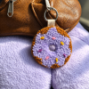 Purple donut punch needle 2-in-1 accessory used as a bag charm