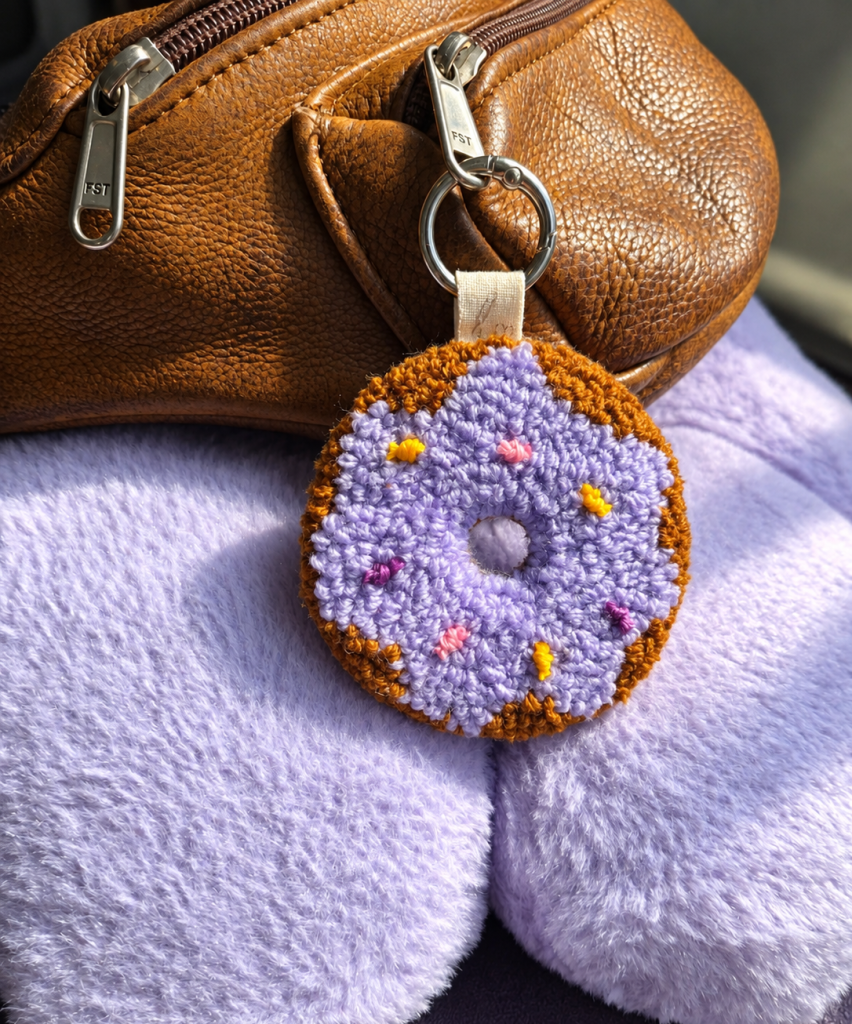 Purple donut punch needle 2-in-1 accessory used as a bag charm