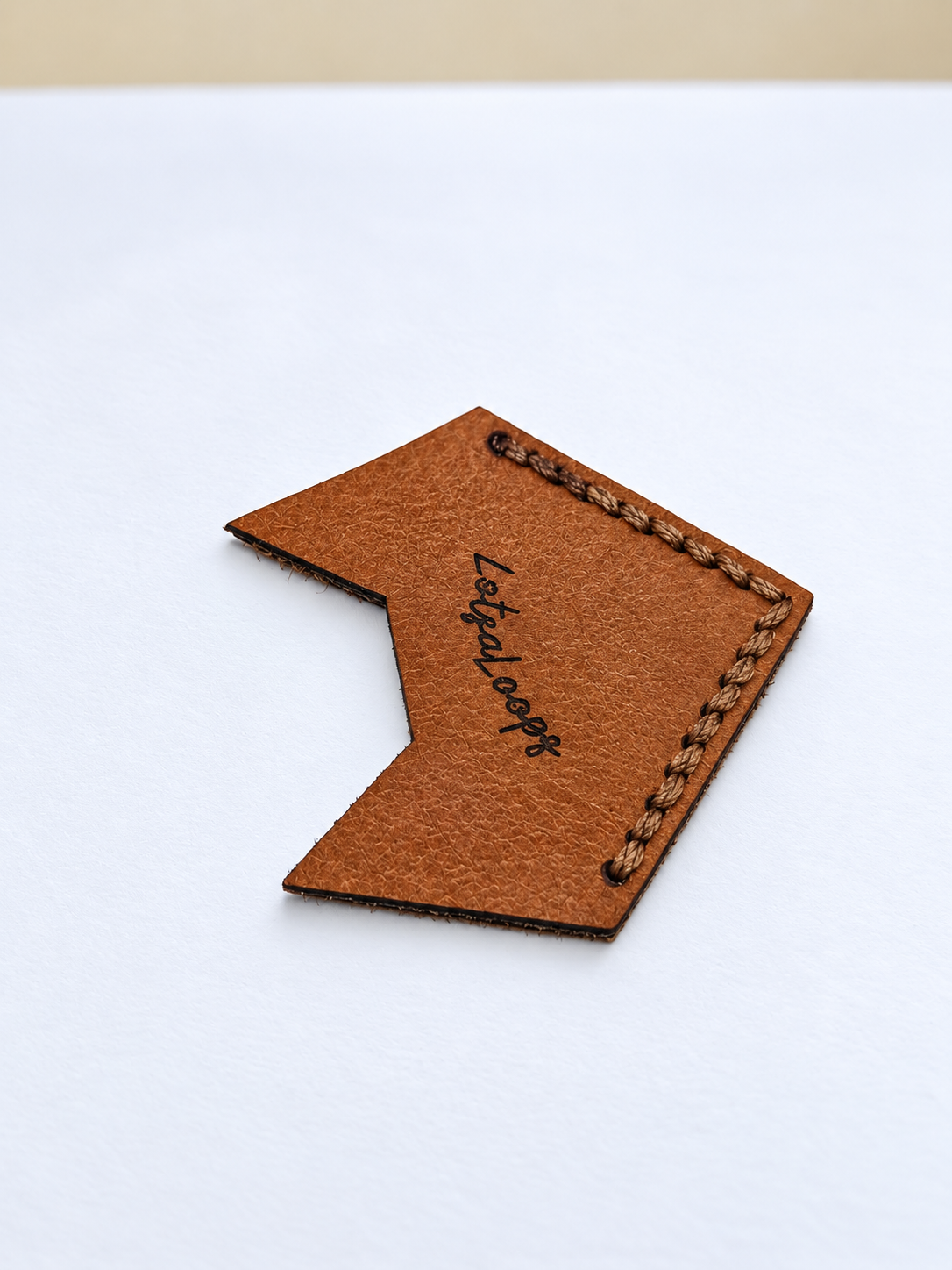 Back of handmade leather fox corner bookmark with LotsaLoops logo and hand-stitched edging
