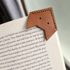 Front of leather fox corner bookmark on a book page showing the cut-out fox face and hand stitching