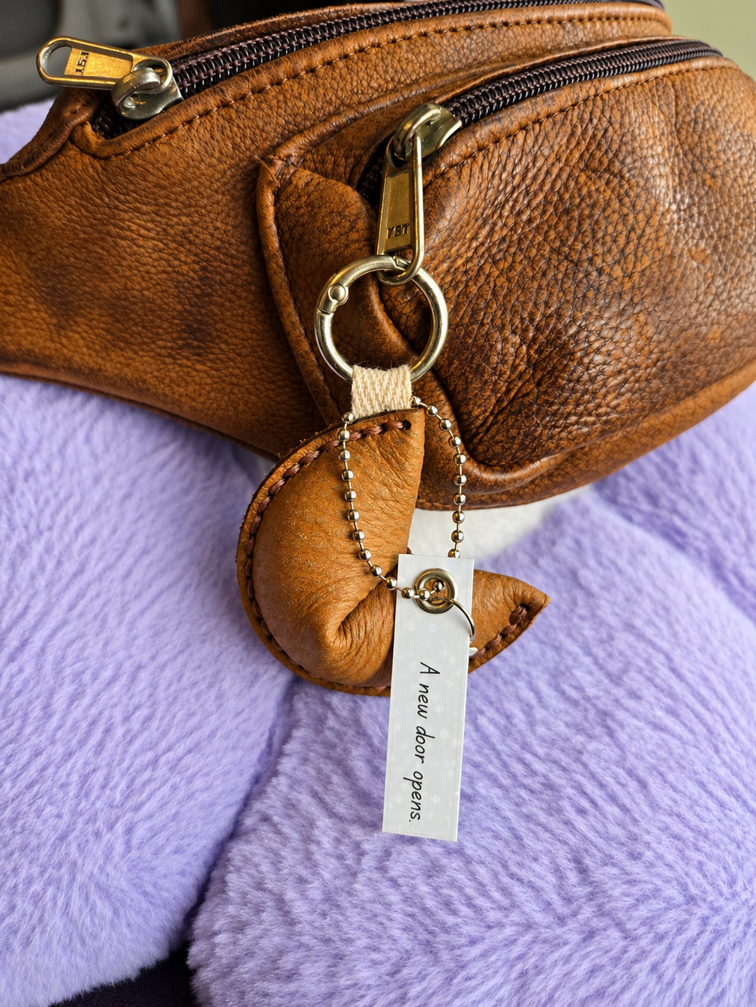 Light brown leather fortune cookie keyring and bag charm attached to handbag