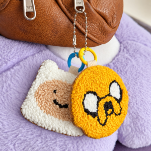 Handmade Finn and Jake punch needle duo bag charms with genuine leather backing, attached to a brown leather bag.